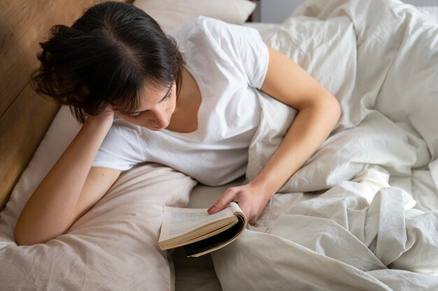 menina esticada na cama lendo um livro