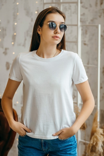 Menina estilosa com camiseta branca e óculos escuros, posando no estúdio