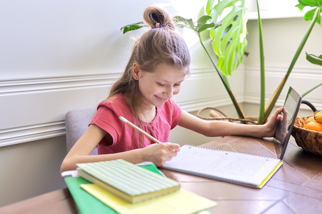 Foto menina estudando em casa usando o tablet digital. ensino à distância, aula online, videoconferência, aulas escolares em formato eletrônico. escola moderna, tecnologia, educação, conceito de crianças.