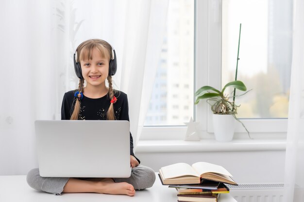 Menina estudando online usando o laptop em casa