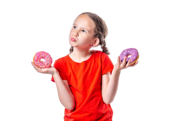 Menina europeia bonitinha com tranças escolhendo donuts isolados no fundo branco.
