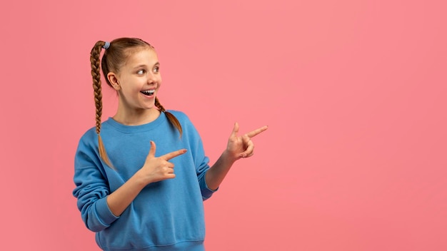 Menina excitada apontando com ambas as mãos para o lado