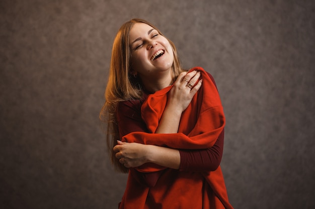 Foto menina experimentando um suéter vermelho em um fundo cinza