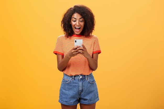 Menina expressando entusiasmo e alegria olhando para o smartphone.