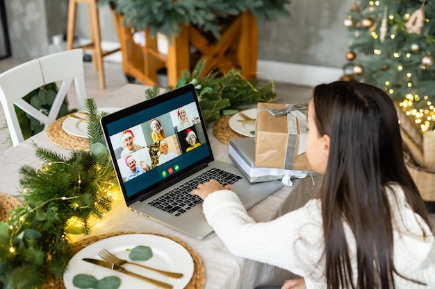 Menina falando e feliz ano novo em um laptop. Parabéns on-line.