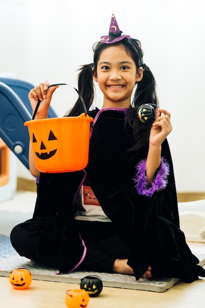 Foto menina fantasiada de halloween com balde de doces e abóbora