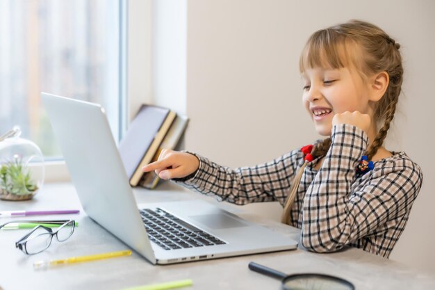 Menina fazendo a lição de casa em casa e usando um laptop