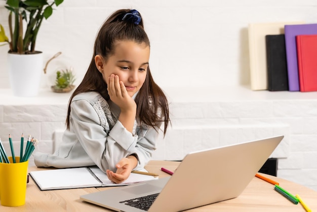 Menina fazendo a lição de casa em casa e usando um laptop