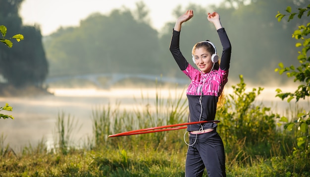 Menina fazendo bambolê ao ar livre perto do lago