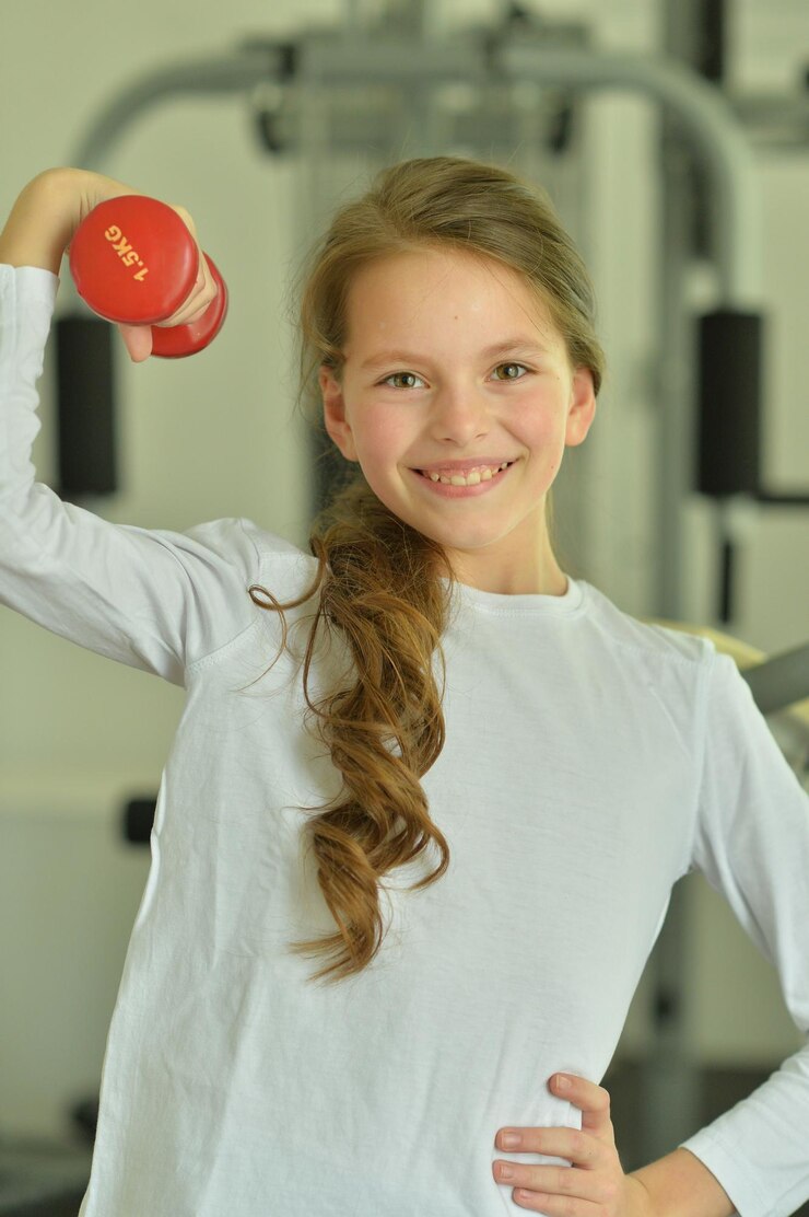 Foto menina fazendo exercícios com haltere no ginásio