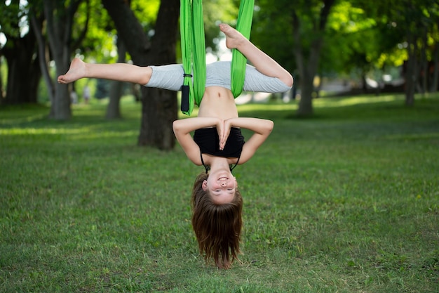 Menina fazendo exercícios de ioga com uma rede no parque