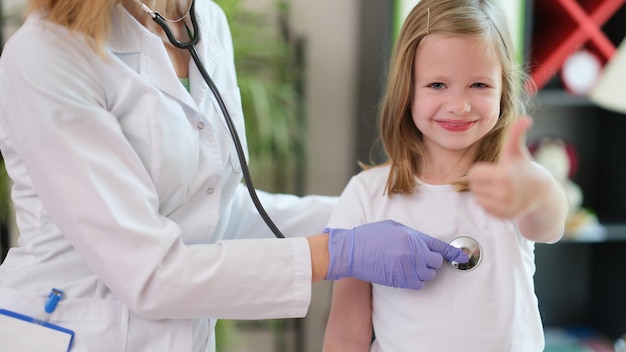 Menina fazendo gesto de polegar para cima na consulta médica conceito de seguro infantil medina