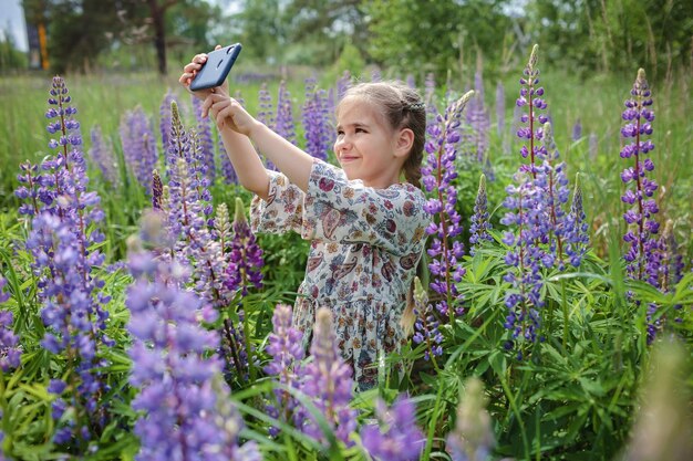 Menina fazendo selfie foto entre tremoços roxos no campo florescente jovem blogueiro no verão