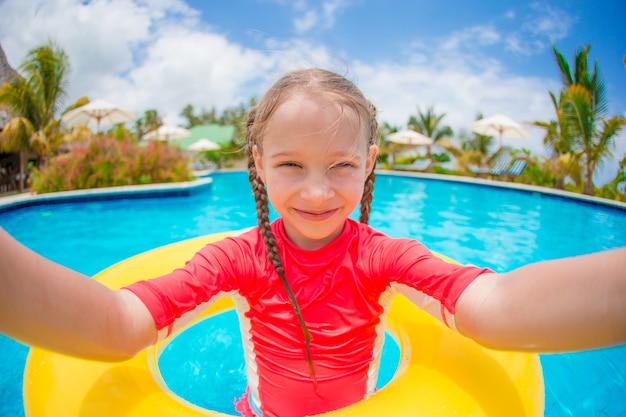 Menina fazendo selfie no anel de borracha inflável na piscina