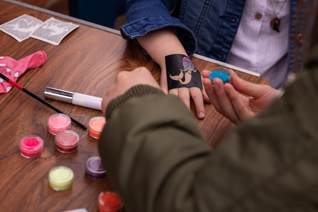 Menina fazendo tatuagem de glitter na festa de aniversário