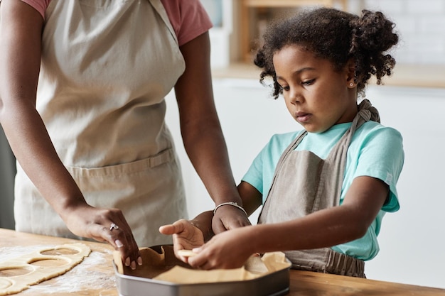 Menina fazendo torta com a mãe