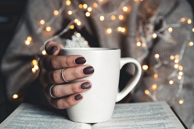 Menina fazendo uma pausa com uma xícara de café fresco, depois de ler livros ou estudar. manicure