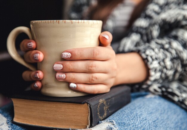 Menina fazendo uma pausa com uma xícara de café fresco depois de ler livros ou estudar