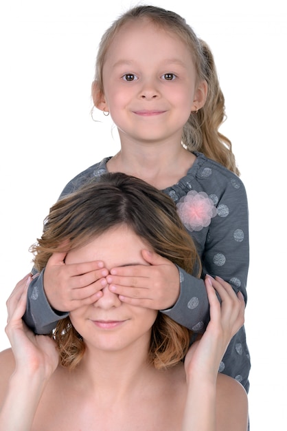 Menina fecha os olhos da mãe e sorri.