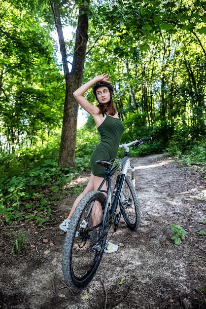 Menina feliz anda de bicicleta na floresta em dia quente de verão