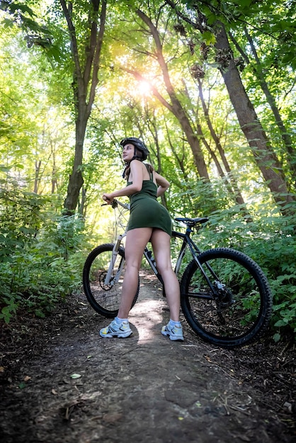 Menina feliz anda de bicicleta na floresta no dia quente de verão estilo de vida