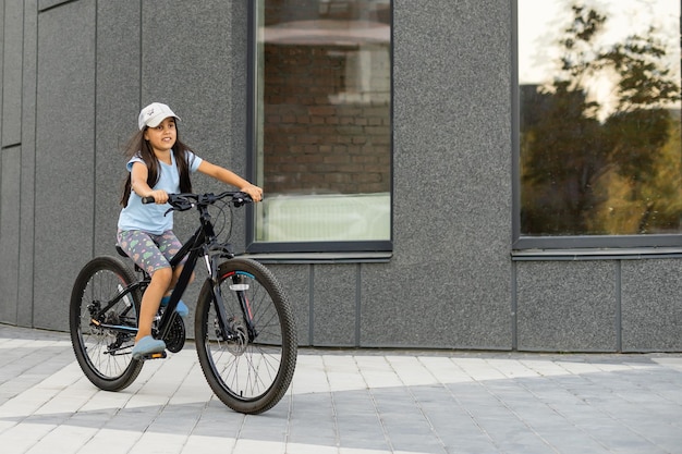 Menina feliz andando de bicicleta na cidade