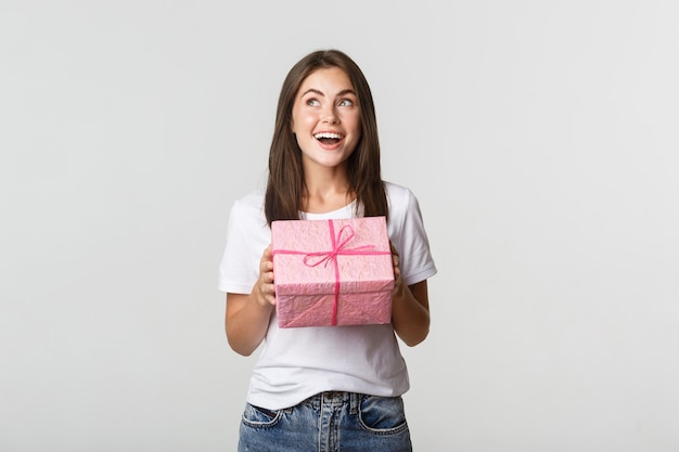 Menina feliz aniversário surpresa recebendo presente embrulhado, branco.