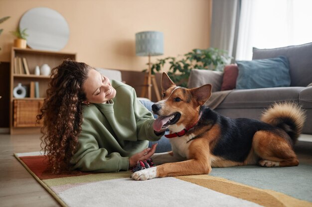 Menina feliz brincando com cão deitado no chão em casa