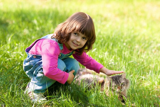 Menina feliz brincando com gato na grama