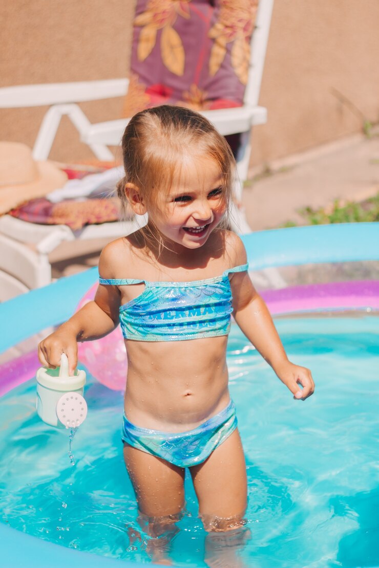 Menina feliz brincando na piscina inflável infantil