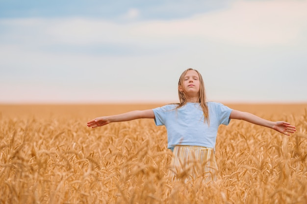 Menina feliz caminhando em campos de trigo dourados