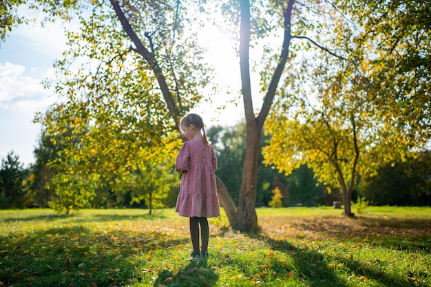Foto menina feliz coleta e brinca com folhas caídas no outono no parque outono