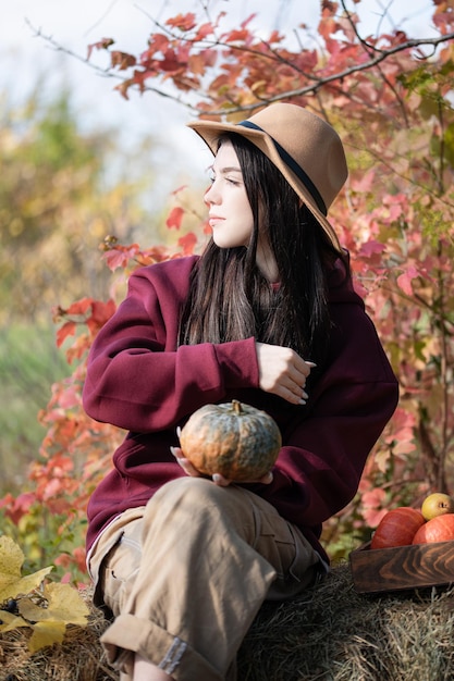 Menina feliz com abóbora no jardim de outono