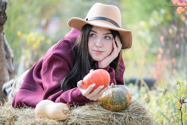 Menina feliz com abóbora no jardim de outono
