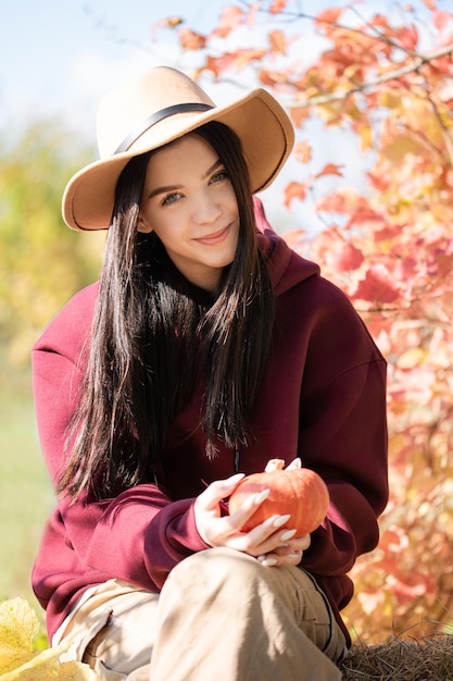 Menina feliz com abóbora no jardim de outono