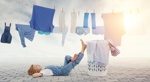 Foto menina feliz com balde de roupas lavadas. mídia mista