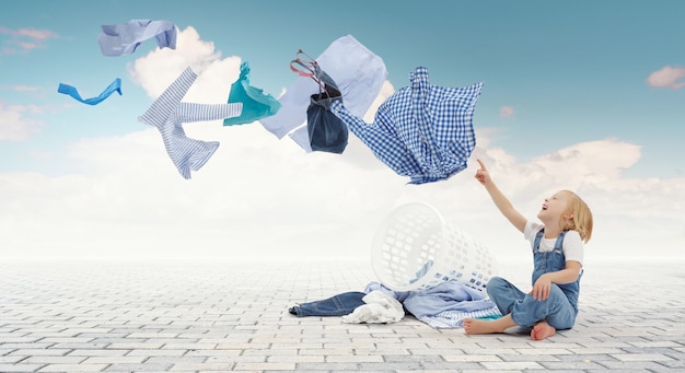 Menina feliz com balde de roupas lavadas. Mídia mista