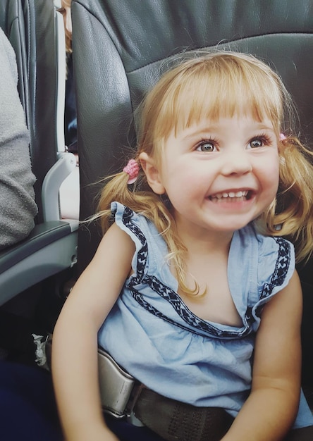 Menina feliz com cabelos loiros no assento do veículo