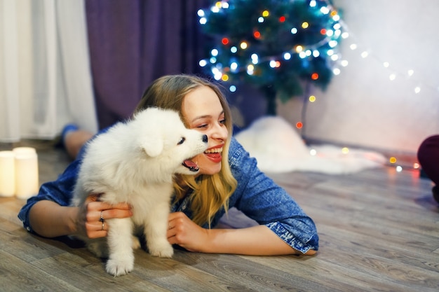 Menina feliz com cachorro husky samoiedo em decorações de Natal