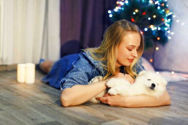 Menina feliz com cachorro husky samoiedo em decorações de Natal