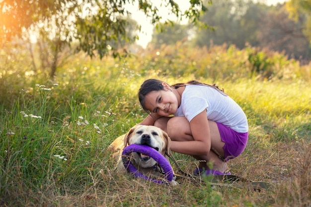 Menina feliz com cachorro labrador retriever brincando no jardim de verão