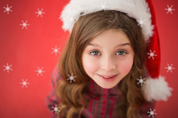 Menina feliz com chapéu de Papai Noel contra flocos de neve