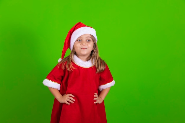 Menina feliz com chapéu de Papai Noel em fundo verde Linda garota vestida para o natal sorrindo