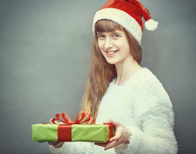 Menina feliz com chapéu de Papai Noel, tendo um Natal