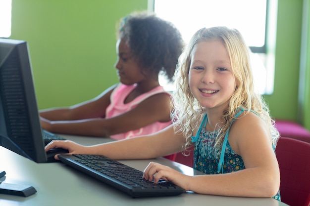 Menina feliz com colega usando computadores