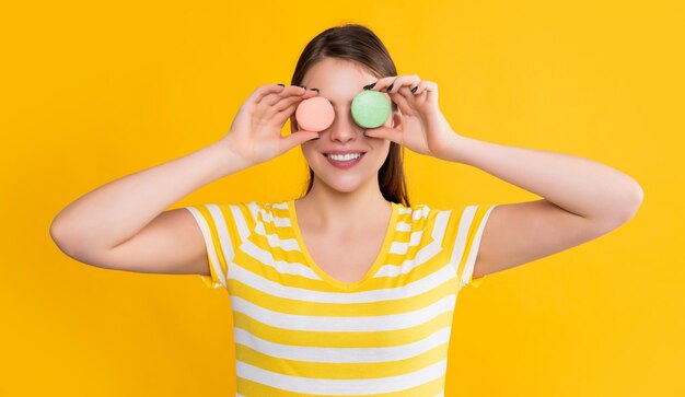 Menina feliz com macaron em fundo amarelo