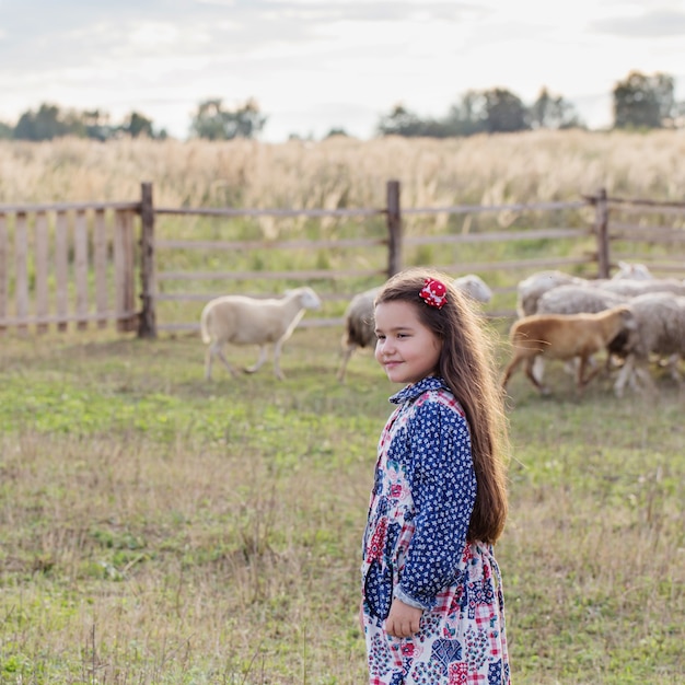 Menina feliz com ovelhas na fazenda