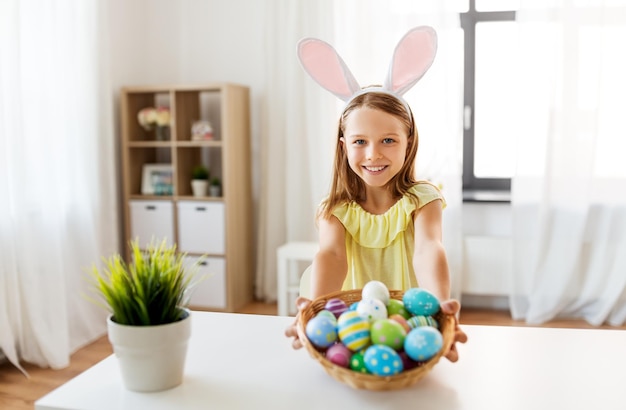 menina feliz com ovos de Páscoa coloridos em casa