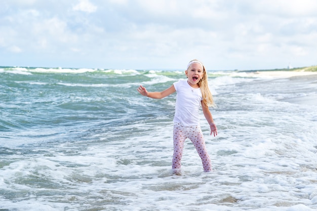 Menina feliz com roupas na praia do mar báltico, no espeto da curlândia, na lituânia.