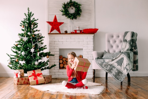 Menina feliz com um presente perto da árvore de natal